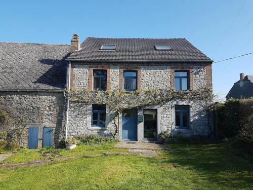una antigua casa de piedra con puertas azules y un patio en Gîte 7ici, en Blaimont