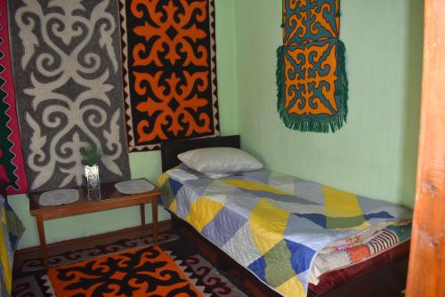 a small bedroom with a bed and a table at Guest House Oimo in Balykchy