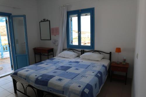 a bedroom with a blue and white bed and a window at Taxiarchis Studios in Áyios Yeóryios