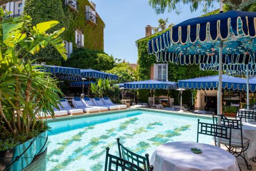 a swimming pool with blue umbrellas and tables and chairs at Le Yaca Saint-Tropez in Saint-Tropez