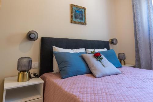 a bed with blue pillows and a flower on it at Bougainvillea house with private garden in Kalamata