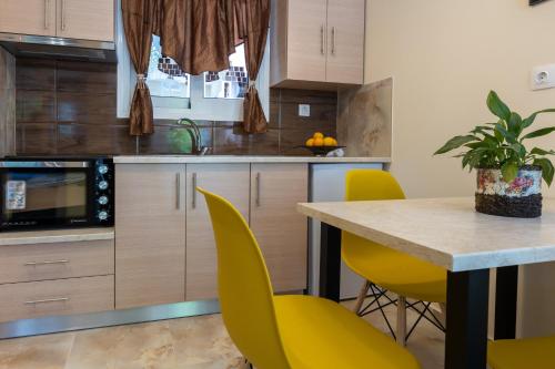 a kitchen with yellow chairs and a table at Bougainvillea house with private garden in Kalamata