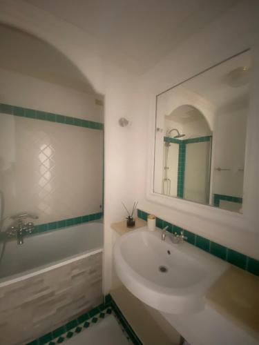uma casa de banho com uma banheira, um lavatório e um espelho. em Residence Gli Oleandri 114 em Liscia di Vacca