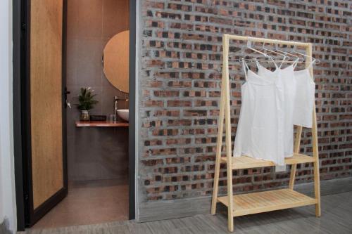 a wooden rack with a white shirt hanging on a brick wall at ᴛᴀᴍ ᴄᴏᴄ ᴄᴏᴄᴏᴏɴ ʜᴏᴍᴇsᴛᴀʏ in Ninh Binh