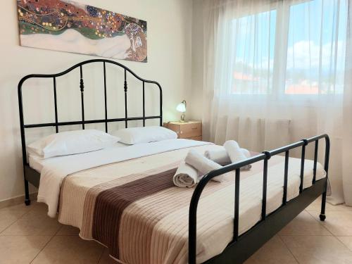 a bedroom with a bed with white sheets and a window at Argiro's Apartment in Iraklitsa