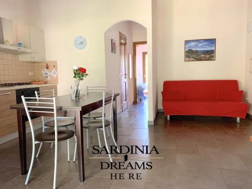 a kitchen and dining room with a red couch at Villetta Sapphire con piscina in Costa Paradiso