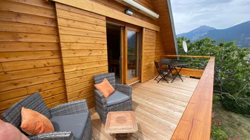 a wooden deck with two chairs and a table at Chalet Chalvet Begat in Embrun