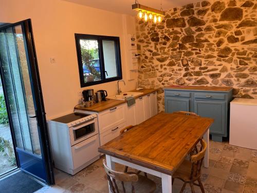een keuken met een houten tafel en een stenen muur bij Les 3 pigeons in Bressuire