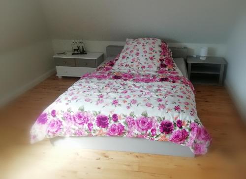 a bed with a pink and white comforter on it at Haus Ferchen in Enge-Sande