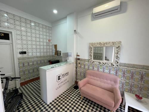 un salon avec une chaise rose et un miroir dans l'établissement Concept Guest House, à Elvas