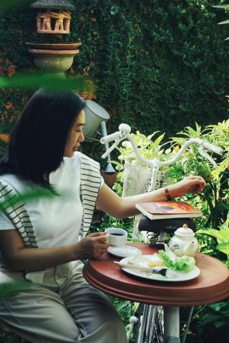 a woman sitting at a table with a cup of coffee at Mekong Pottery Homestay, Green-Friendly & Boat Tour in Vĩnh Long