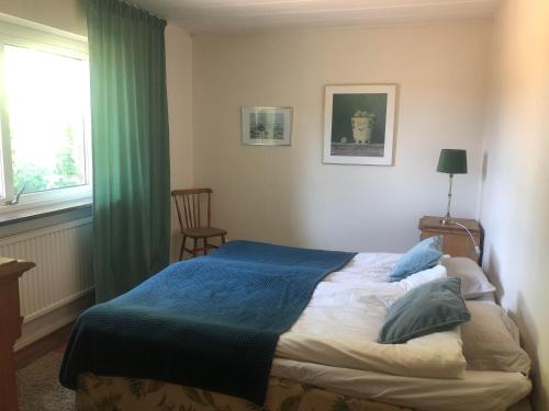 une chambre avec un lit avec une couverture bleue et une fenêtre dans l'établissement Gatehouse at unique farm, neighbour to yaks & emus, à Höör