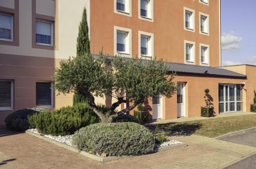 a tree in front of a building at Mercure Lyon Est Chaponnay in Chaponnay