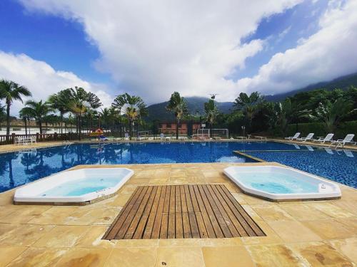 a large swimming pool with two swimming trays in it at Maresias, Chalé H29 em condomínio de frente a Entrada 18 da praia e dentro da Mata Atlântica in São Sebastião