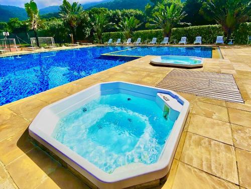 a hot tub sitting next to a swimming pool at Maresias, Chalé H29 em condomínio de frente a Entrada 18 da praia e dentro da Mata Atlântica in São Sebastião