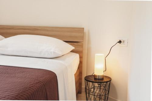 a bed with a white pillow and a lamp on a table at Ana in Preko