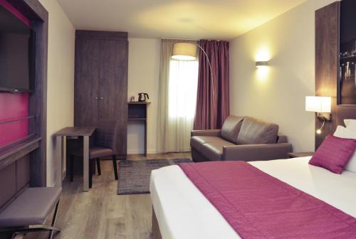 a hotel room with a bed and a chair at Mercure Lyon Est Chaponnay in Chaponnay
