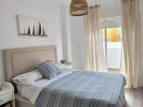 1 dormitorio con 1 cama con edredón azul en Apartamento en Rota con piscina y parking junto al mar en Rota