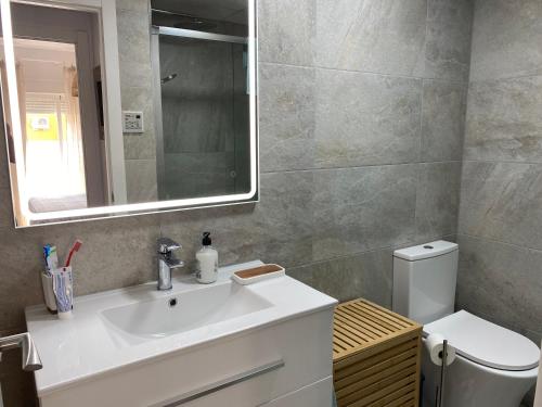 a bathroom with a sink and a toilet and a mirror at Apartamento en Rota con piscina y parking junto al mar in Rota