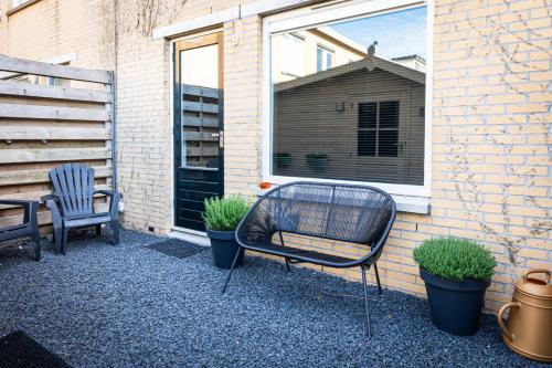 a patio with two chairs and plants in front of a building at Studio Puuur in Zandvoort