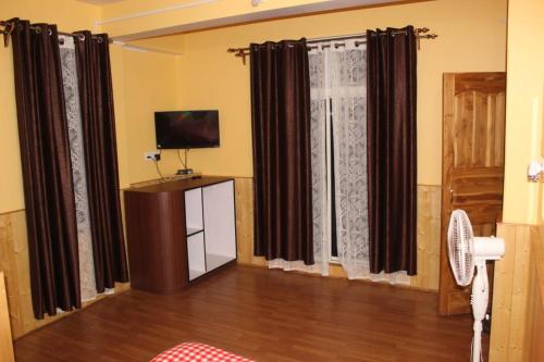 a living room with black curtains and a television at Hotel Seren Point in Kalimpong
