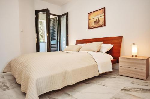 a white bedroom with a large bed and a lamp at Ana in Preko