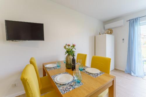 a dining room with a wooden table and yellow chairs at Visit Baltic Apartament Morski Piasek in Sarbinowo