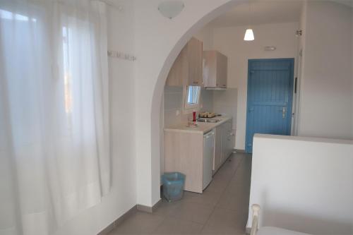 a kitchen with an archway and a blue door at Taxiarchis Studios in Áyios Yeóryios