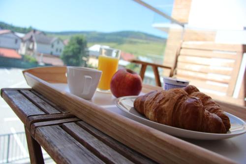 a plate of bread and an apple and orange juice on a table at APARTMÁN K2 Zuberec in Zuberec