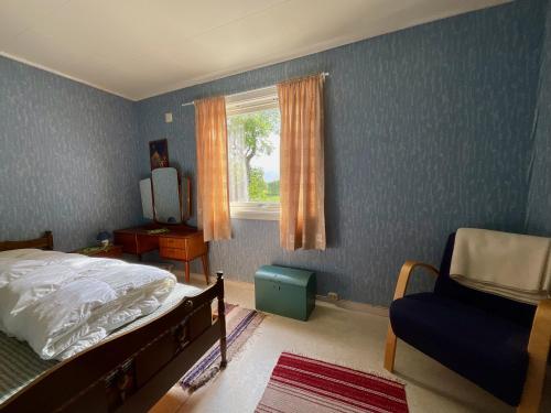 a bedroom with a bed and a chair and a window at The Birch Grove House Lofoten in Alstad