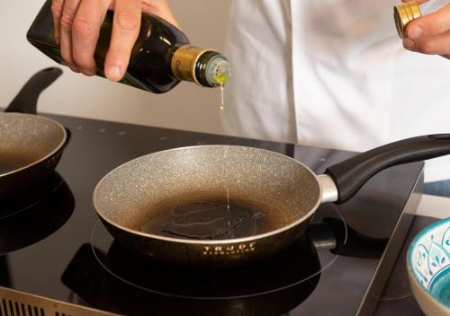 a person is pouring liquid into a pan on a stove at Hotel Cristallo in Riccione