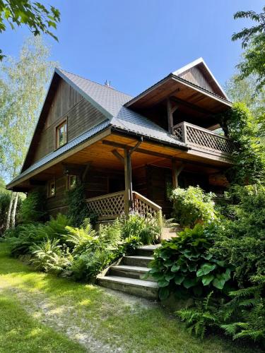 Une grande maison en bois avec des escaliers se trouve juste devant. dans l'établissement Dom z bali przy szlaku, à Kasina Wielka