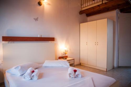um quarto com uma cama branca e toalhas em Dreams Beach Apartments Katelios em Kateleios