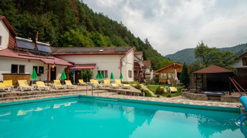 a resort swimming pool with chairs and mountains in the background at Pensiunea Alpin in Păltiniş