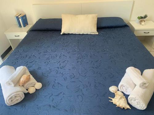 ein blaues Bett mit Handtüchern und ausgestopften Tieren darauf in der Unterkunft HOTEL LA PERGOLA in Cattolica
