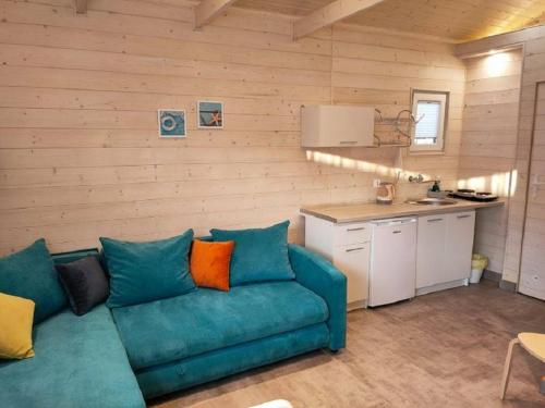 a living room with a blue couch and a kitchen at Ośrodek Madamaku in Sianozety
