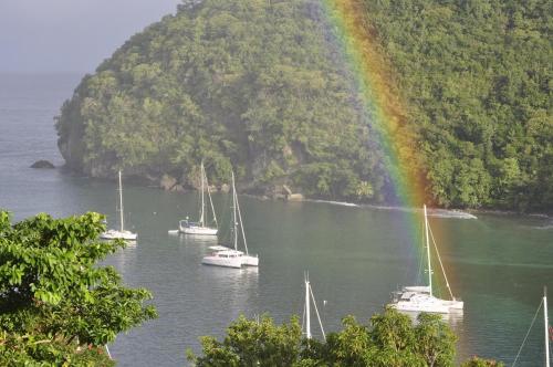 a group of boats in the water with a rainbow at Marigot Palms Luxury Caribbean Apartment Suites in Marigot Bay