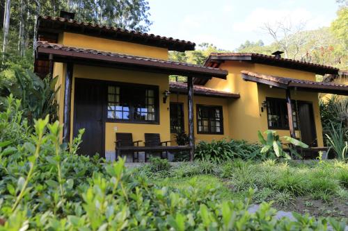 a yellow house with black windows at Auberge Suisse Pousada in Nova Friburgo