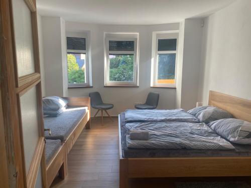 a bedroom with two beds and two chairs and windows at Vila Kosmonautka - Velké Losiny in Velké Losiny
