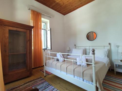 een slaapkamer met een wit bed en een raam bij Rania's Cottage in Lákka