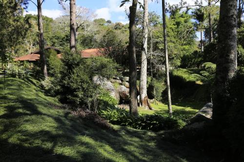 a garden with trees and a house in the background at Auberge Suisse Pousada in Nova Friburgo