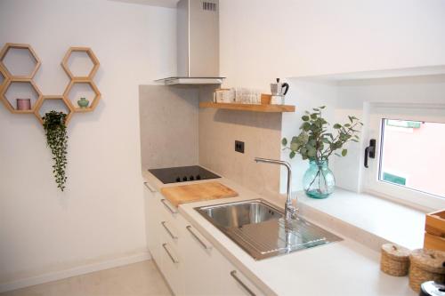 a white kitchen with a sink and a window at Modern and cozy apartments Salt & Pepper in heart of Rovinj in Rovinj