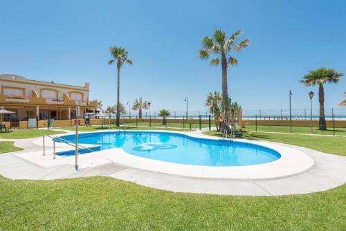 una piscina con palmeras y un edificio en Apartamento 34 La Tortuga I, en Tarifa