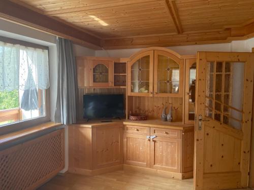 sala de estar con armarios de madera y TV de pantalla plana en Ciasa Fam Comploi, en San Vigilio Di Marebbe