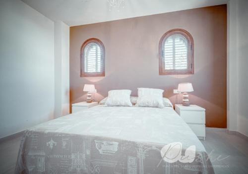 a white bedroom with a large bed with two windows at PUSHE Village Playa Granada Beach&Golf 2 in Motril