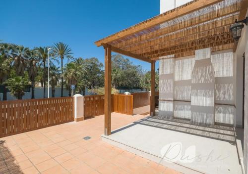 a patio with a pergola and a fence at PUSHE Village Playa Granada Beach&Golf 2 in Motril