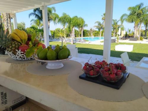 two bowls of fruit on a table with a pool at Tenuta Espada Luxury Residence in Gallipoli