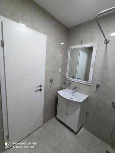 a bathroom with a sink and a shower with a mirror at Apartmani Kula in Tuzla