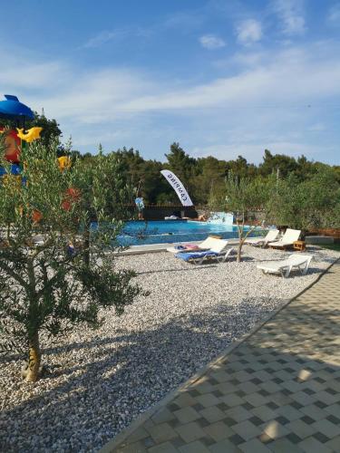 a resort with a pool and chairs and a tree at Camping Volme Tent in Banjole