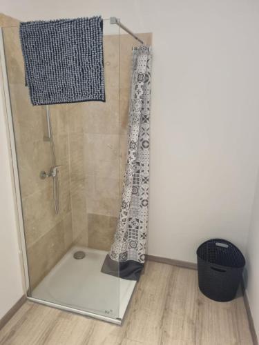 La salle de bains est pourvue d'une douche avec une porte en verre. dans l'établissement Appartement séjour , cure Cransac au 1er étage 2 nuits minimum, à Cransac